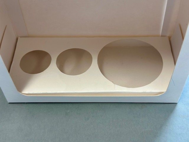 Open cosmetic box with a card insert cut to hold three jars of different sizes
