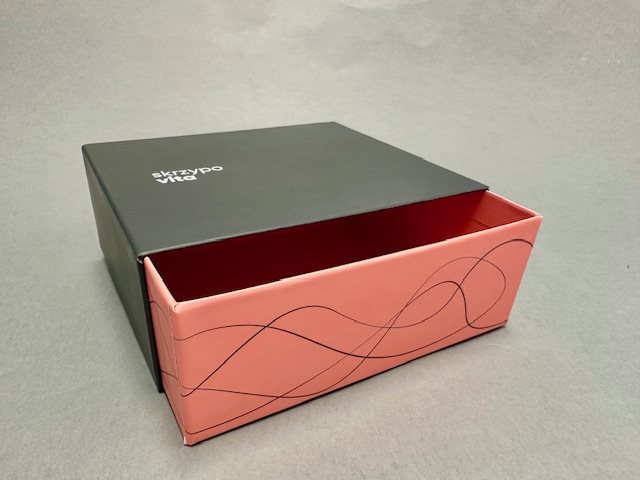 Drawer box with a black sleeve and a pink tray printed with a line pattern